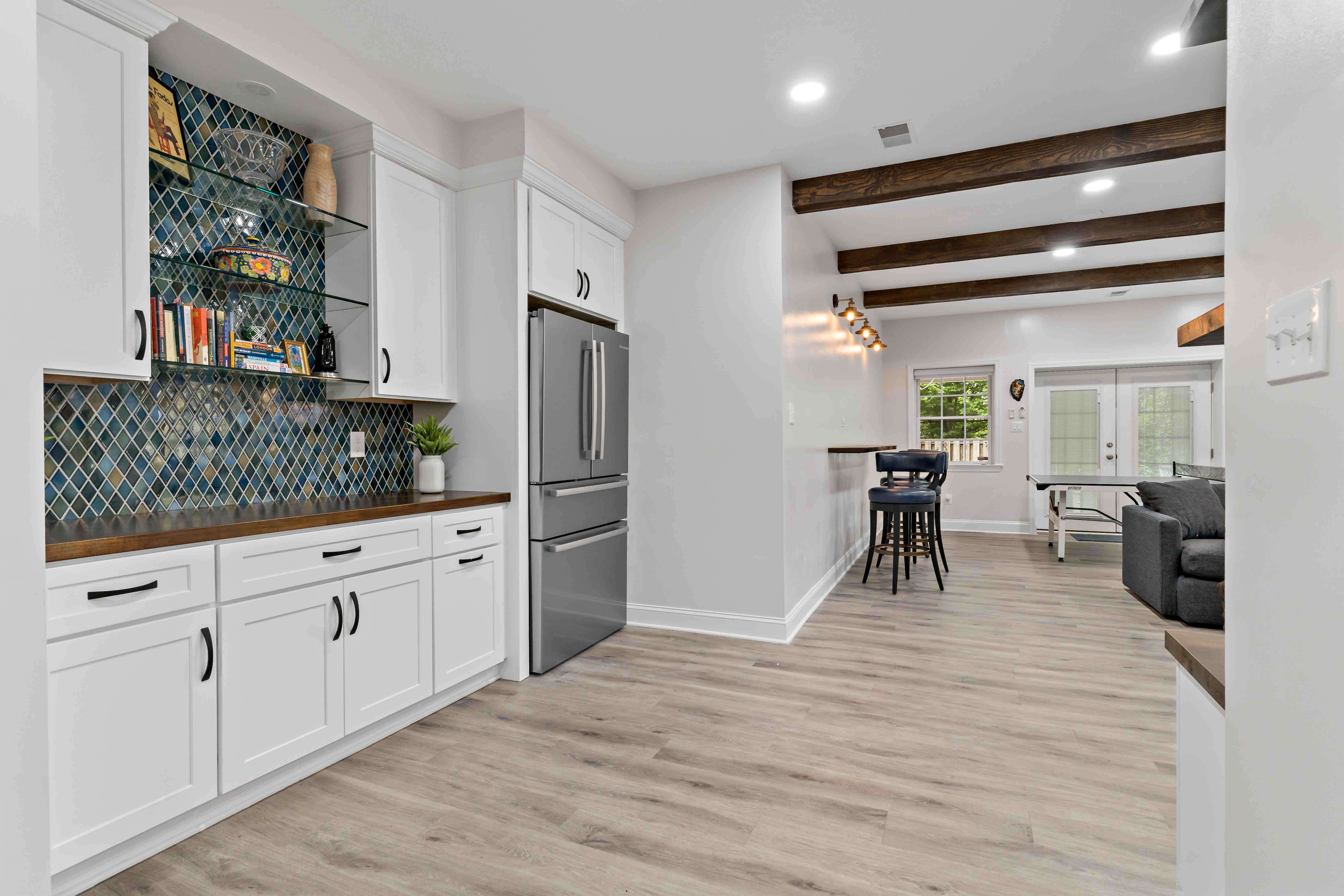 Mini bar on perimeter of basmenet with blue multi-colored backsplash