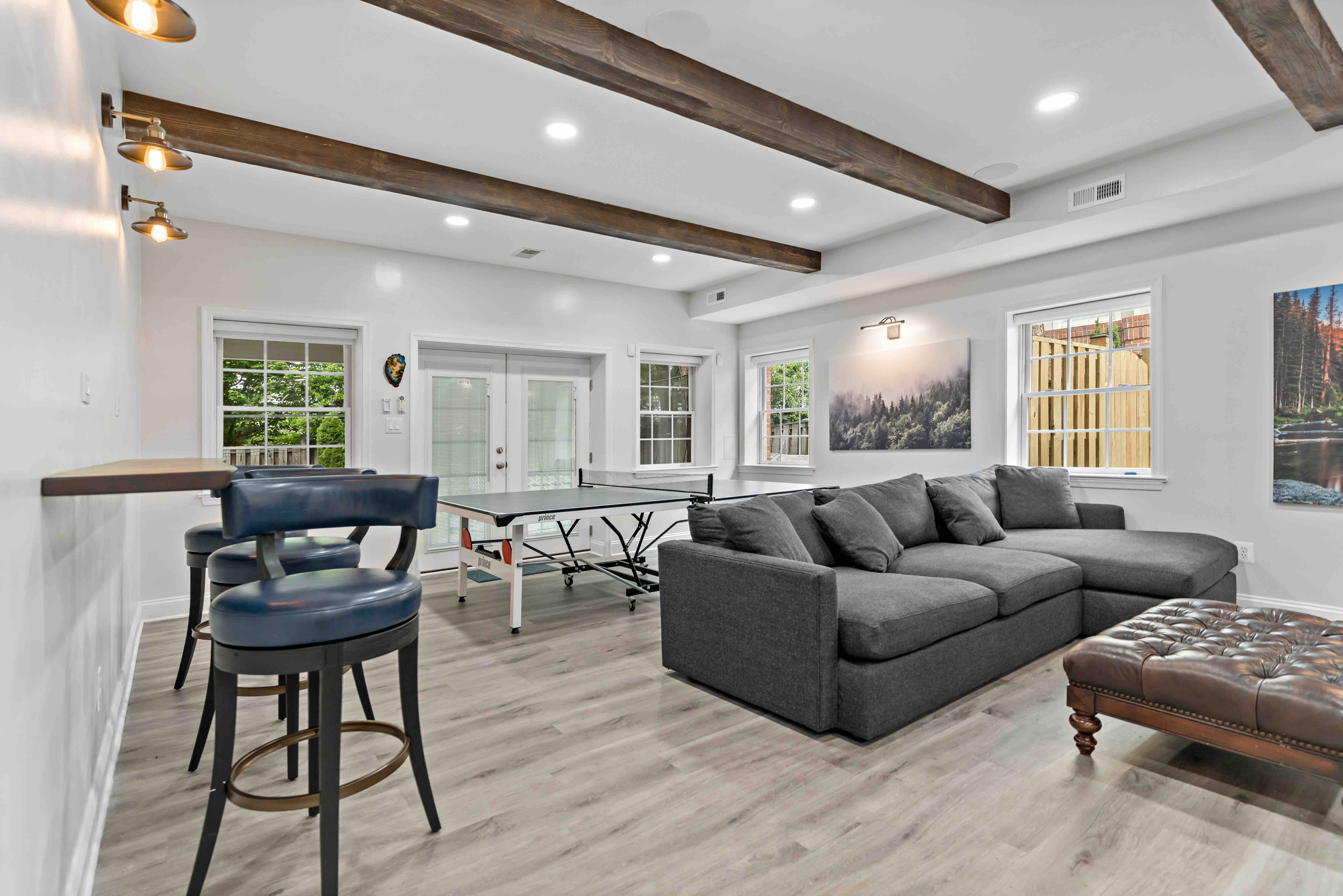 Exposed wood beams and floating bar in remodeled basement