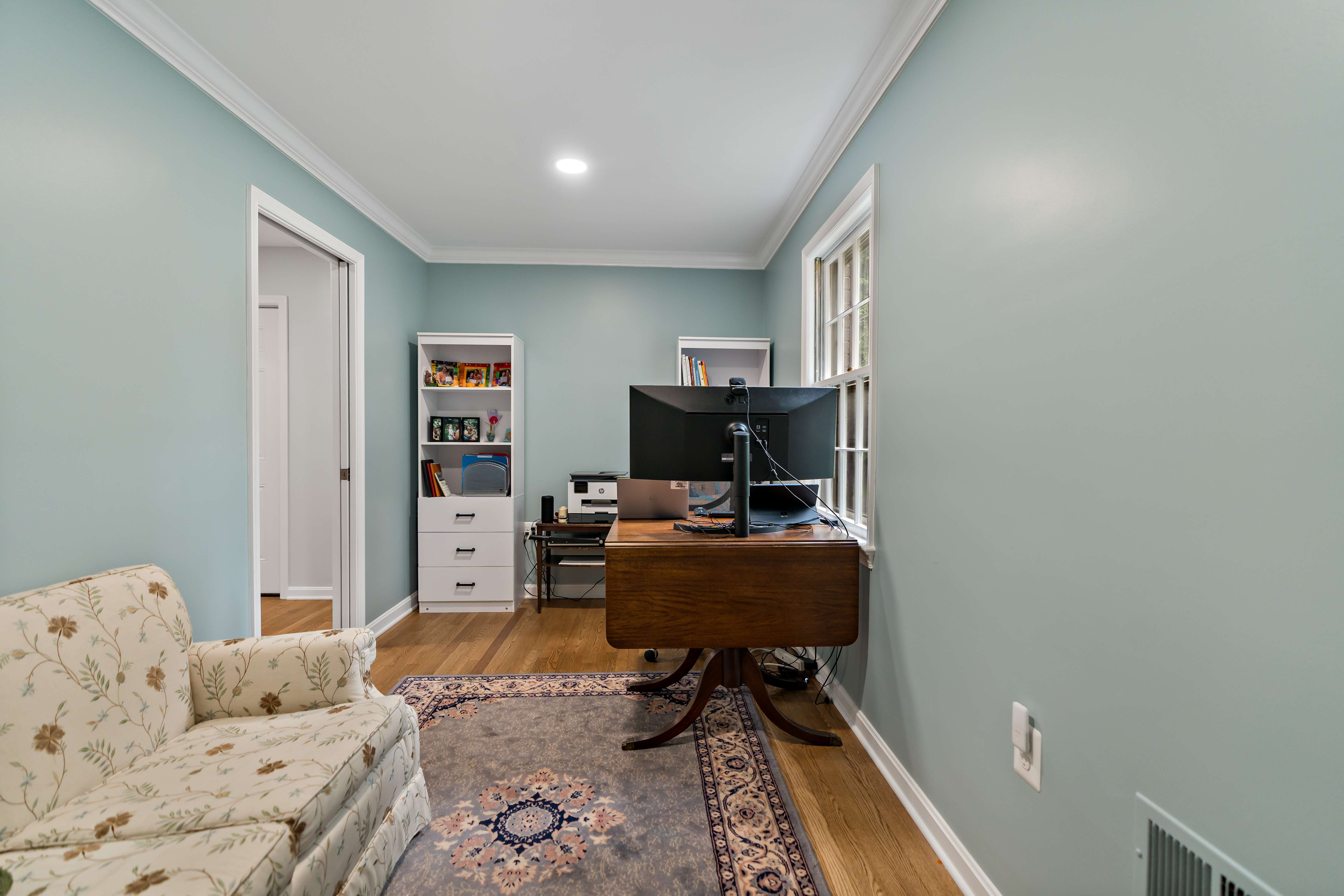 Home office with hard wood floors and rug with couch